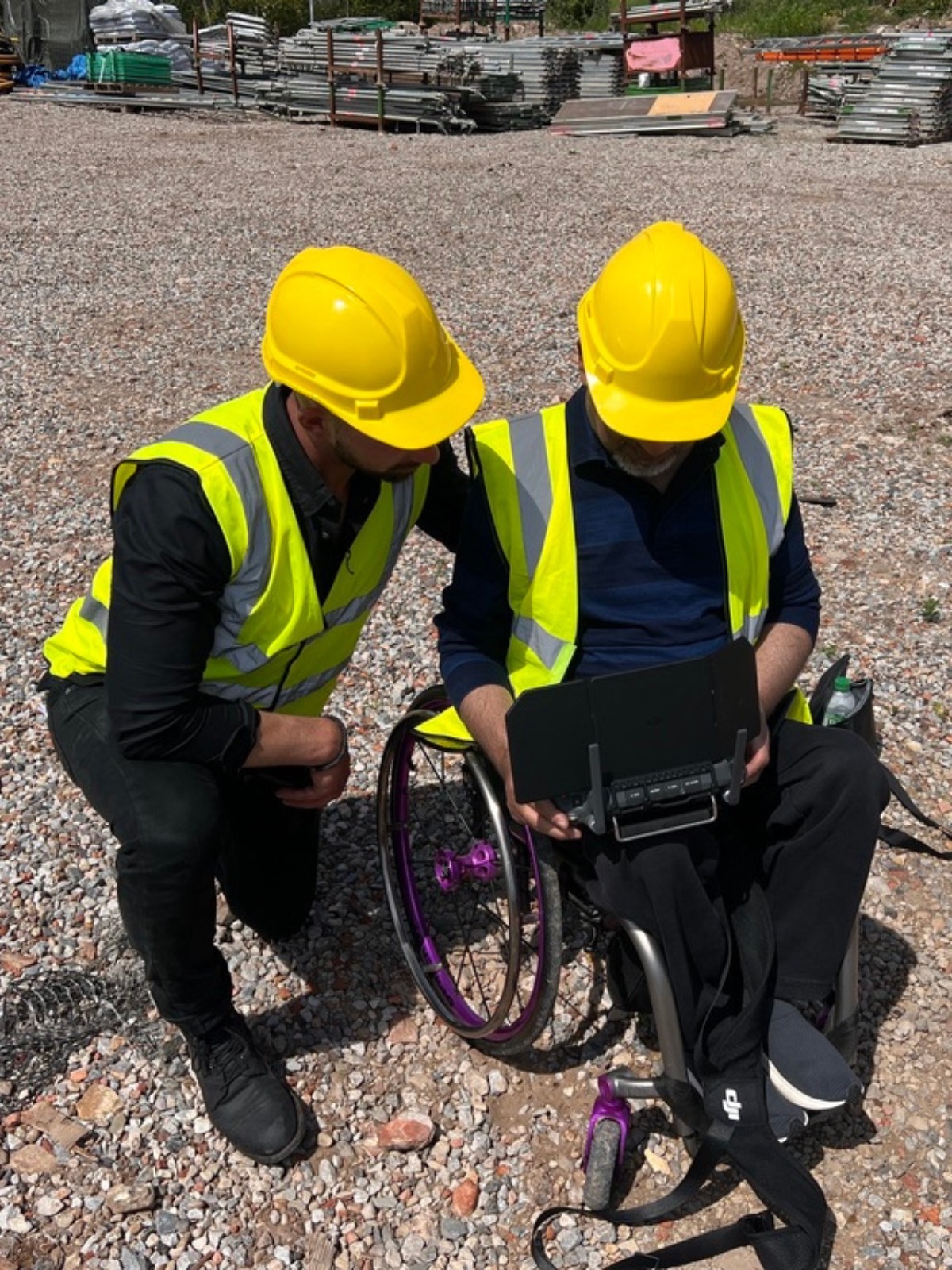 An SBS Foundation instructor teaching a trainee pilot to fly a drone outdoors